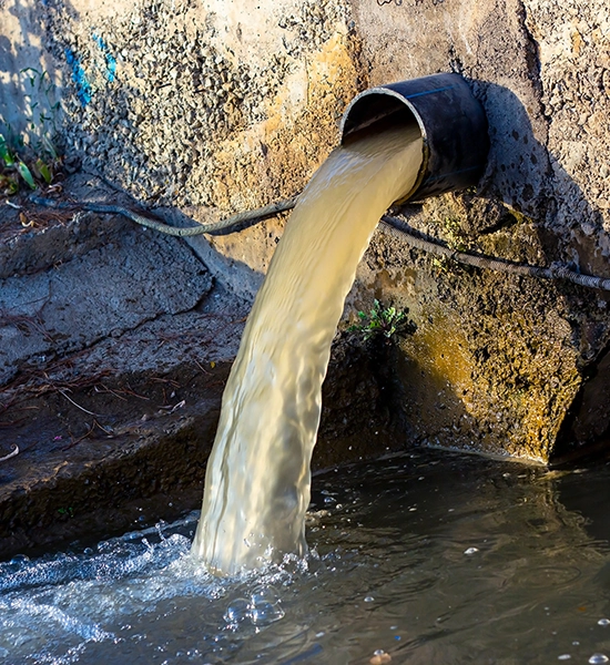 pipe sticking out of cement wall draining brown water into holding pond. Groundwater, Groundwater Testing, Groundwater Lab, Groundwater Contaminants, Groundwater Monitoring, Groundwater Analysis