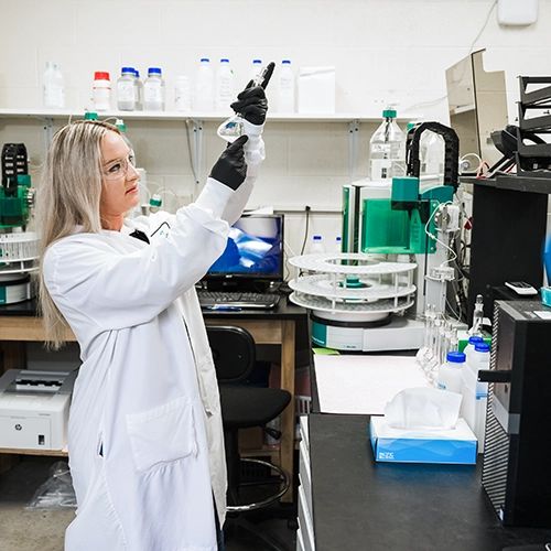 Pace Scientist holding up beaker looking at contents.