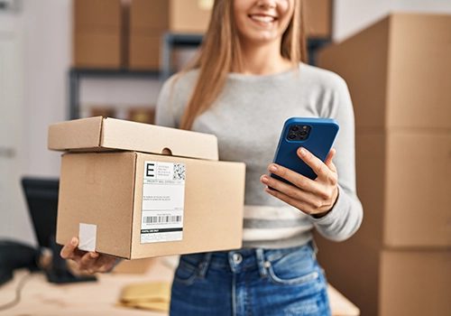 woman holding packages while looking at phone. Pace services for consumer goods industry