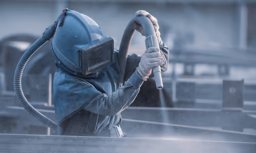 Worker sandblasting in approved Personal Protective Equipment. How is respirable Crystalline Silica Regulated?
