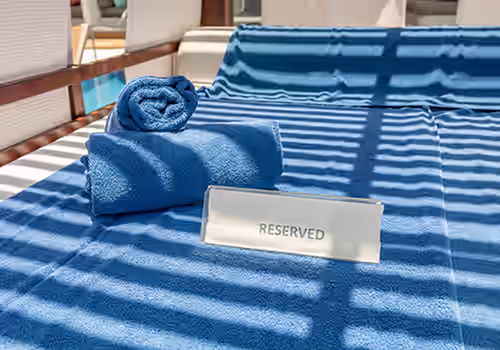 Blue pool lounger with blue towels and Reserved sign at spa pool. Paceº Services for the Hospitality Industry.